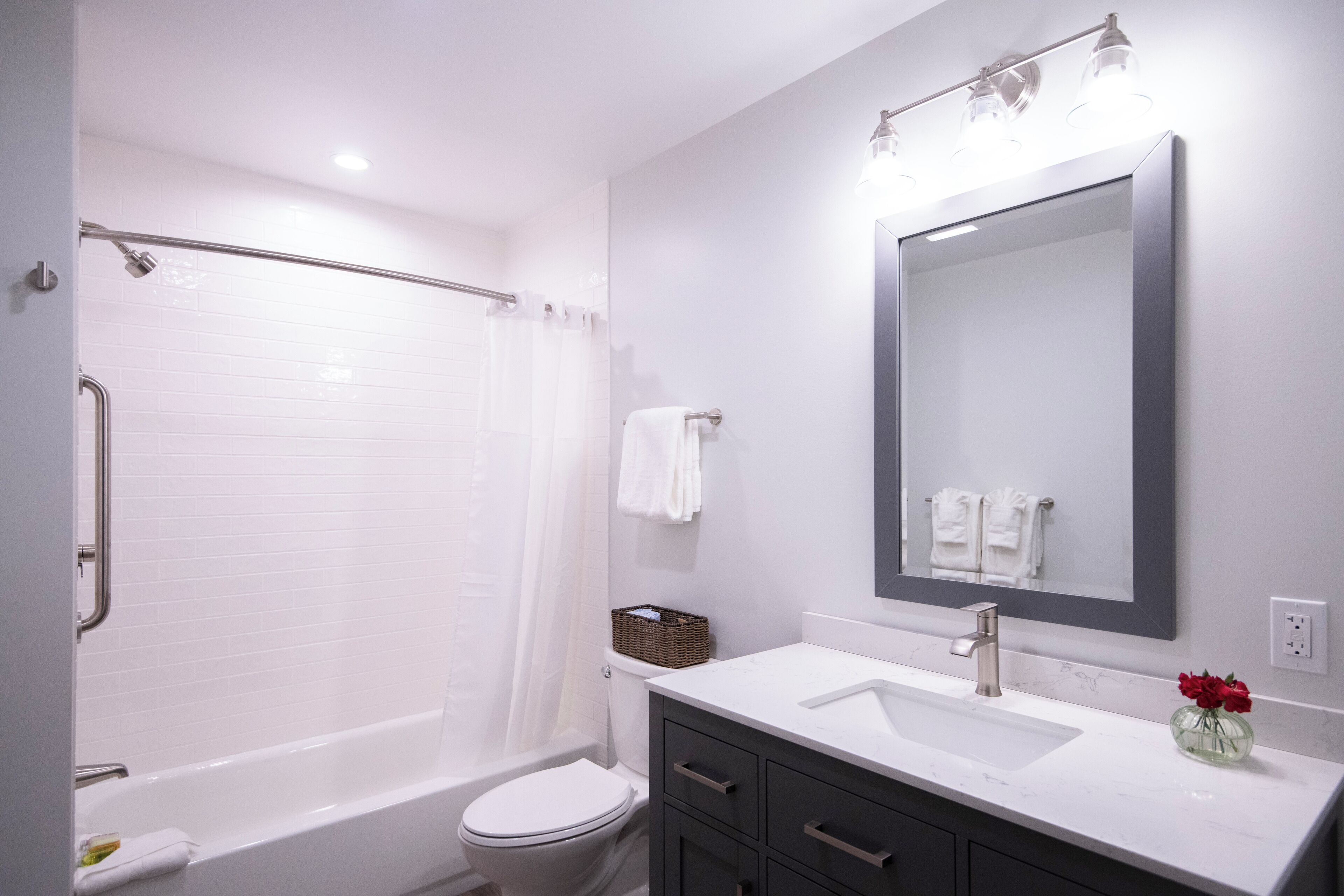 Un baño moderno con bañera, inodoro, tocador con espejo y lavabo.