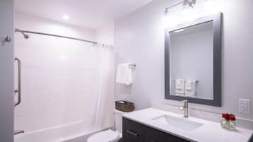 A modern bathroom with a bathtub, toilet, vanity with a mirror, and a sink.