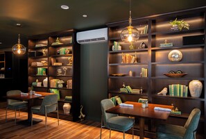 A modern library with wooden bookshelves, a dining area with a table and chairs, and decorative items. - The Pathmaker Hotel (Bar Harbor)