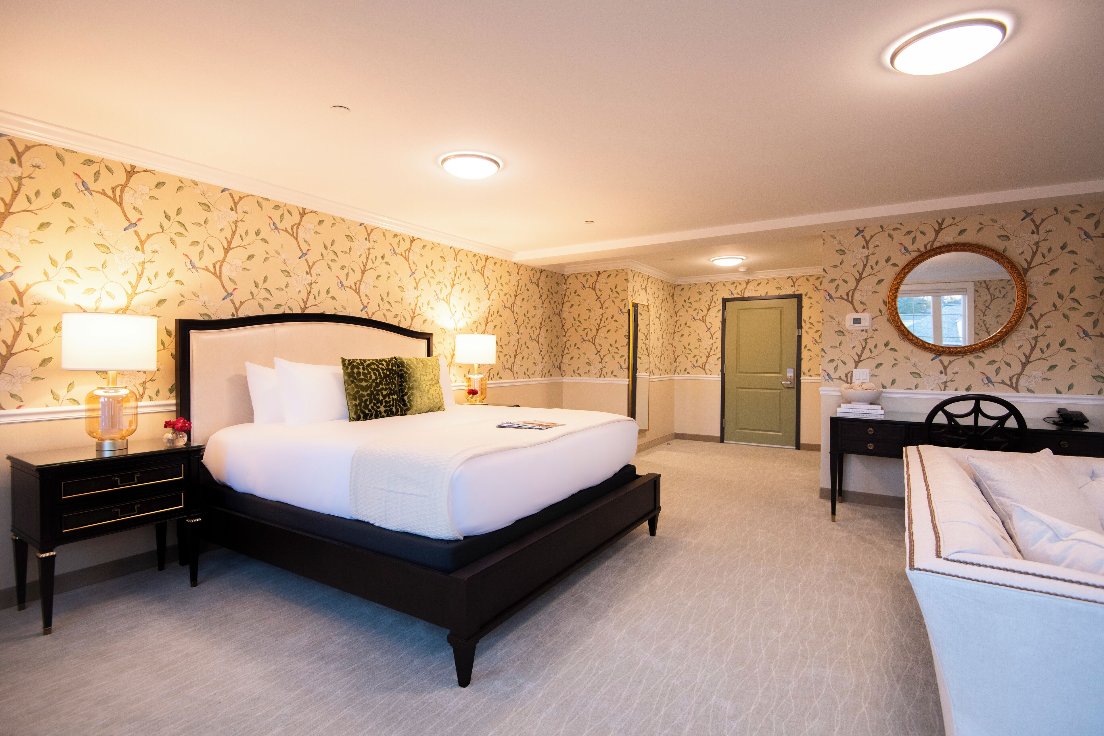 A bedroom with a large bed, bedside tables, a desk, and a chair.