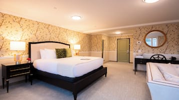 A bedroom with a large bed, bedside tables, a desk, and a chair.