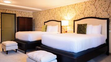 A hotel room with two beds, a wardrobe, a door, and a carpeted floor.