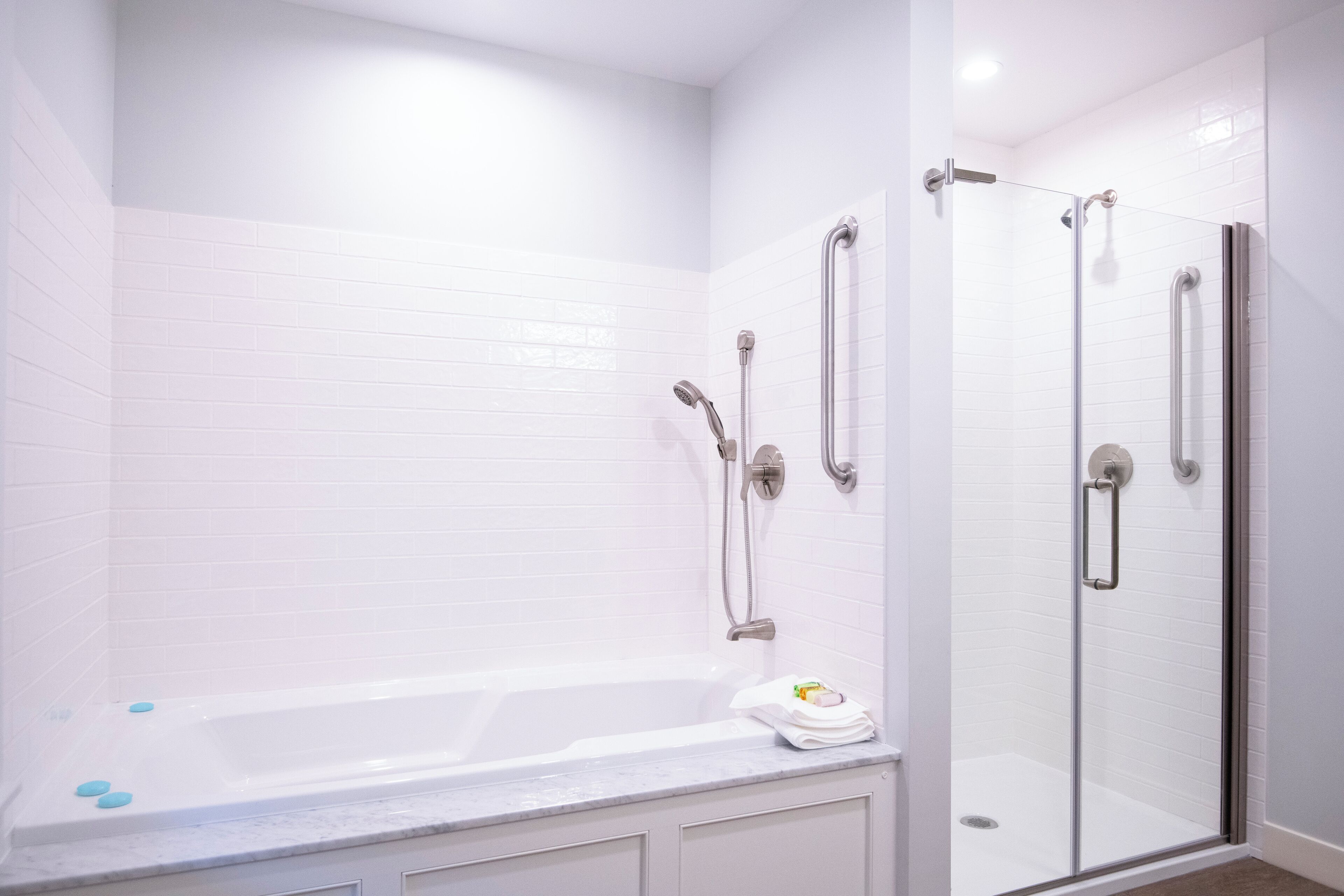 Un baño moderno con ducha de vidrio, bañera y tocador con una toalla.