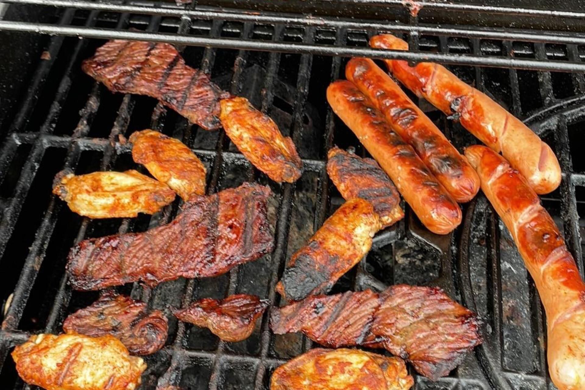 Un barbecue avec différentes sortes de viande en train de cuire.