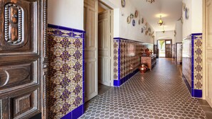A hallway with patterned tiles, a wooden door, and a tiled wall.
