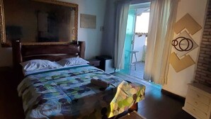 A bedroom with a bed, a dresser, a mirror, and a view of the outside. - Pousada Solar de Tamoios (Cabo Frio)