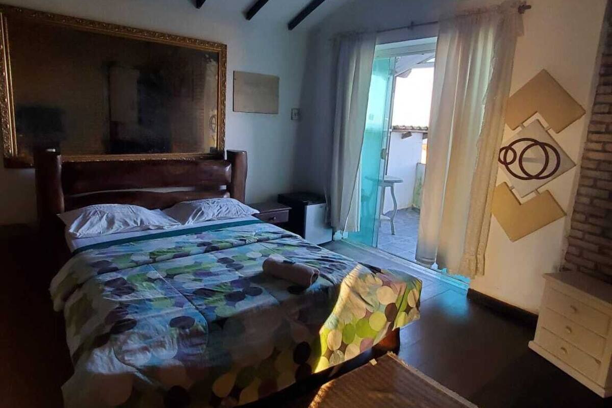 Quarto com cama, penteadeira, espelho e vista para o exterior.