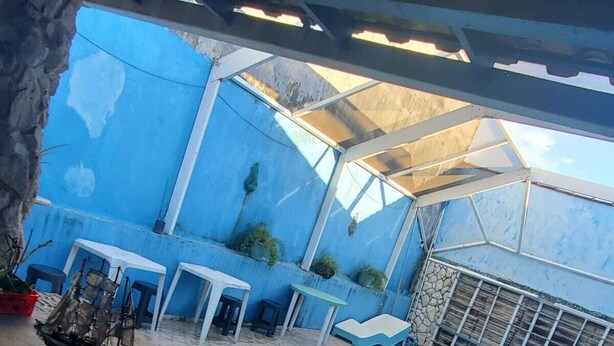 A swimming pool area with a blue-tiled floor, a small ship model, and several tables and chairs. - Pousada Solar de Tamoios (Cabo Frio)