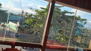 A restaurant with tables covered in red tablecloths and wooden chairs, large windows offering a view of the outdoors. - Pousada Solar de Tamoios (Cabo Frio)
