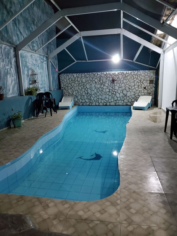 An indoor swimming pool with a stone wall and tiled floor.