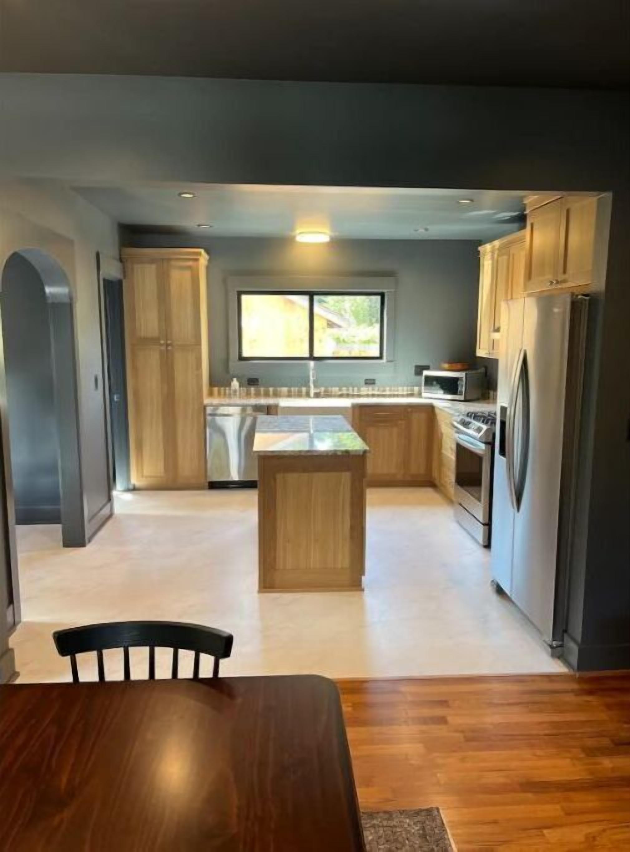Een moderne keuken met houten kastjes, een centraal eiland en een ingebouwde oven.