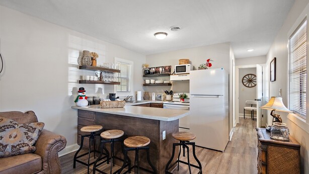 A compact kitchen with a central island, bar stools, and a refrigerator.