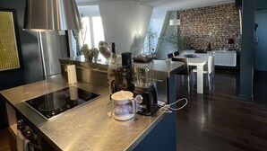 Une cuisine moderne dotée d’un îlot central, d’appareils électroménagers intégrés et d’un coin repas agrémenté d’un mur en pierre.
