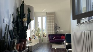 Un salon moderne avec un plancher en bois, un canapé violet, une table basse et diverses plantes en pot.