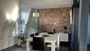 Un coin repas avec un mur en briques, une grande fenêtre et une plante en pot.