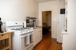 Efficient kitchen with gas stove, oven, refrigerator, and ample storage.