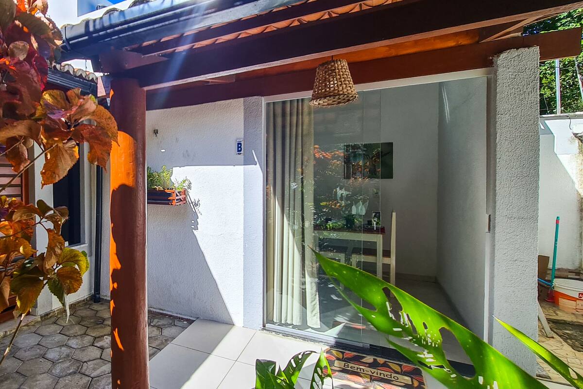 Un patio couvert agrémenté d’une pergola, doté d’une porte-fenêtre et d’un sol carrelé.