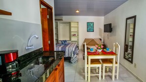A compact kitchen with a coffee machine, a sink, and a dining area with a table set for two. - Chalé Recanto dos Passarinhos  (Tibau do Sul)