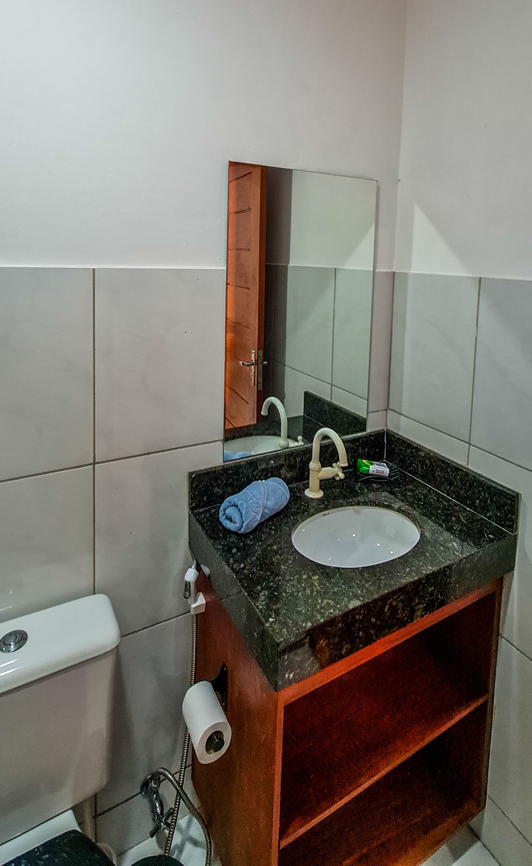 A bathroom with a sink, mirror, toilet, and towel.