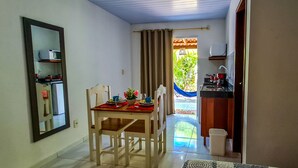 A dining area with a table set for two, a mirror on the wall, and a view of the outside through a door. - Chalé Recanto dos Passarinhos  (Tibau do Sul)