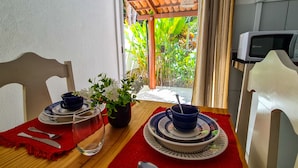 A dining table set with plates, bowls, and a glass, with chairs and a potted plant. - Chalé Recanto dos Passarinhos  (Tibau do Sul)