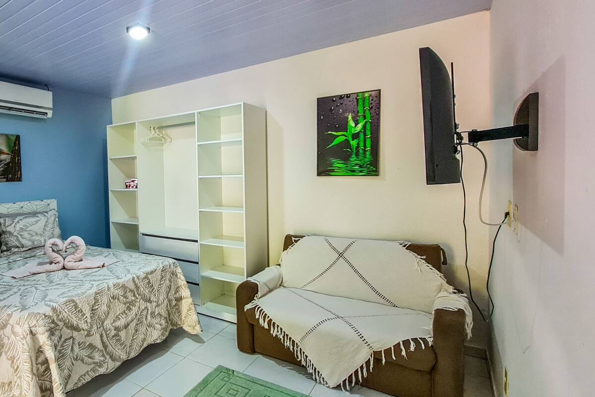 Une chambre à coucher avec un lit, une armoire, un canapé et un tableau au mur.