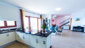 Eine moderne Küche mit weißen Schränken, einer schwarzen Arbeitsplatte und einem großen Fenster.