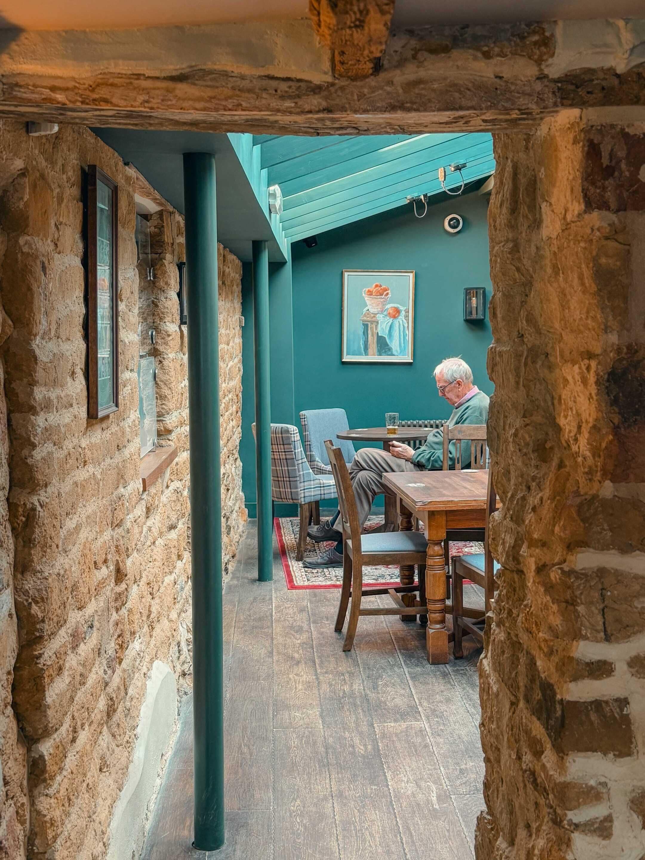 A rustic room with stone walls, a wooden table, and a chair.