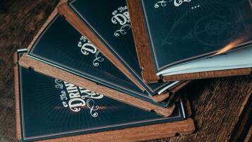 A stack of menu books titled 'The Drinks Menu' on a wooden table.