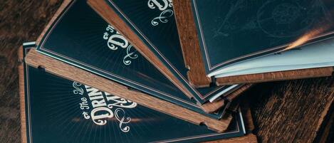 Un montón de libros de menú con el título 'The Drinks Menu' sobre una mesa de madera.