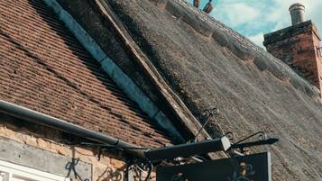 A building with a sign reading 'The Three Pigeons Freehouse,' a stone facade, and a thatched roof.
