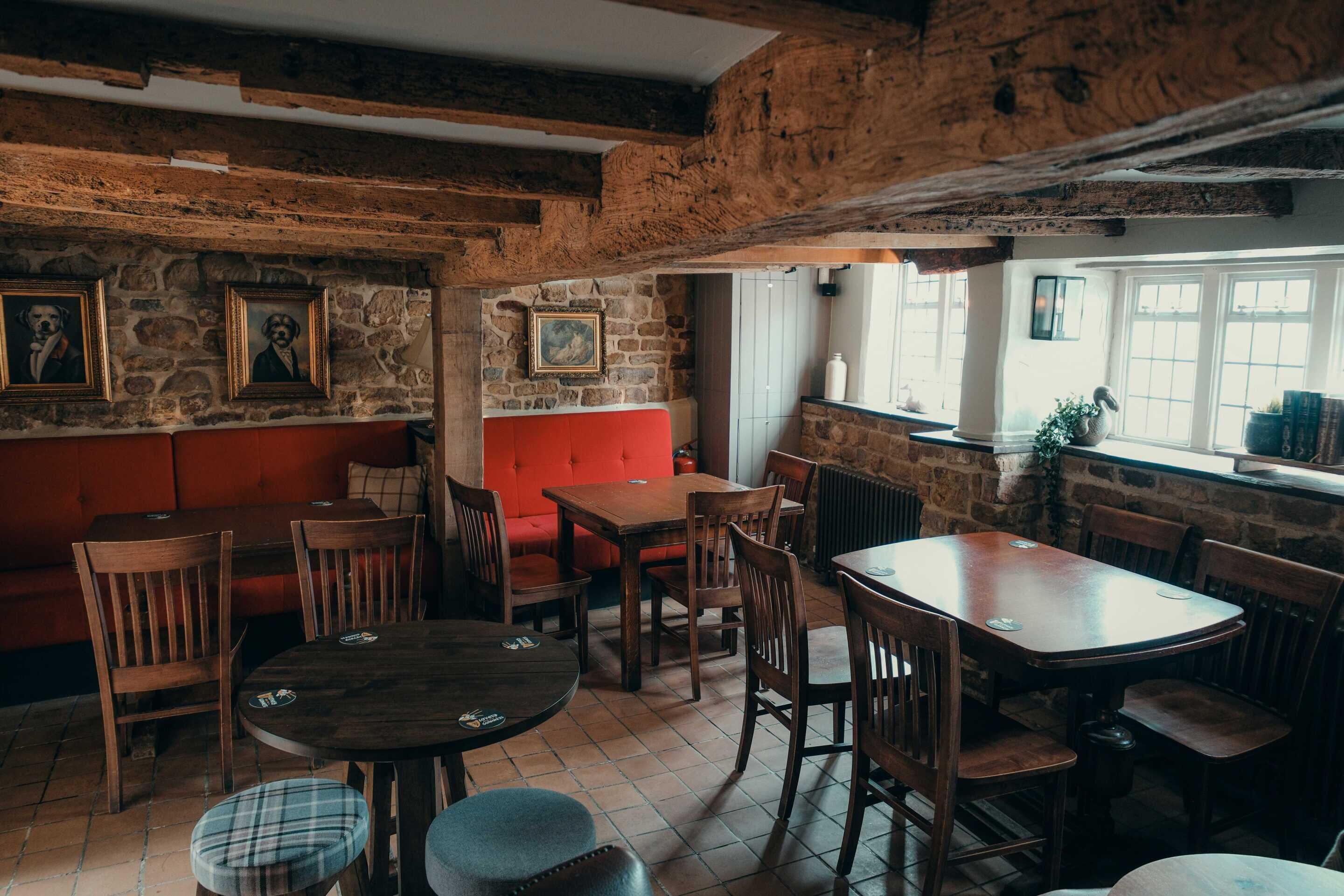 A rustic interior with exposed wooden beams, stone walls, and wooden furniture.