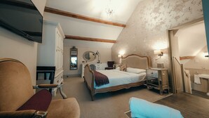 A bedroom with a large bed, a chair, a dresser, a mirror, and a television.