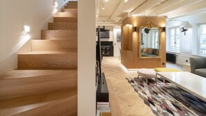 Een modern interieur met een houten trap, een eethoek met een kamerbreed tapijt, en een grote spiegel met een decoratief kader.