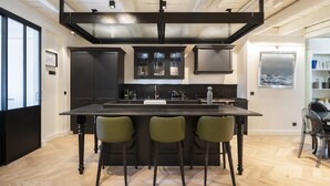 Een moderne keuken met een groot kookeiland, donkere kastjes en een visgraat houten vloer.
