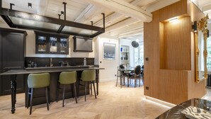 Een moderne keuken met een centraal eiland, barstoelen en een eethoek met tafel en stoelen.