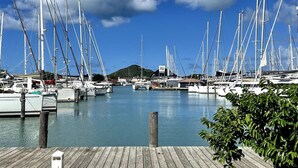 A marina with multiple sailboats docked, wooden piers, and a clear blue sky with clouds. - 4 Guests - Stunning View - Pool - South Finger (Jolly Harbour)
