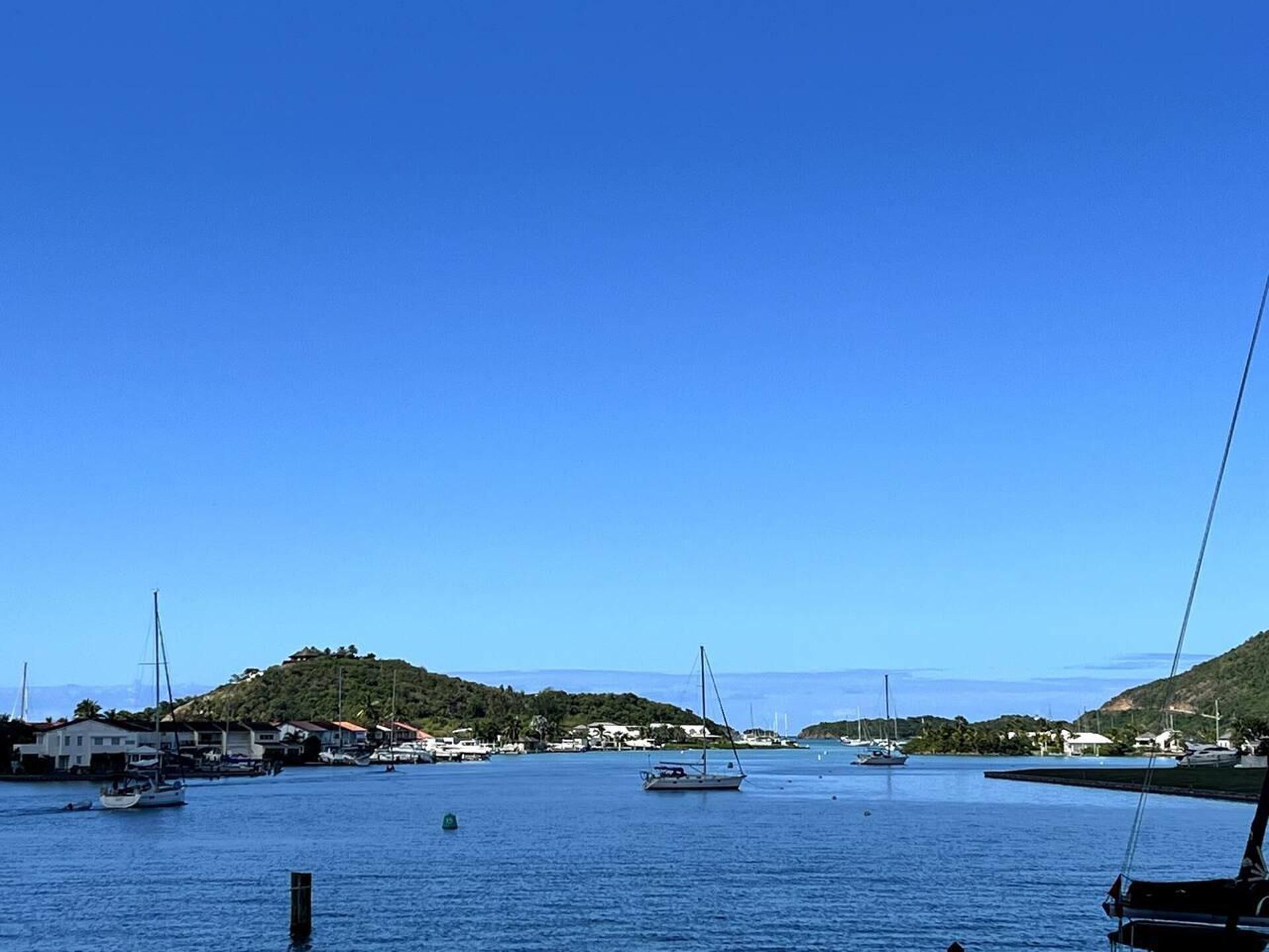 Un puerto deportivo con barcos amarrados, rodeado de colinas y casas.