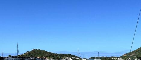 Un puerto deportivo con barcos amarrados, rodeado de colinas y casas.