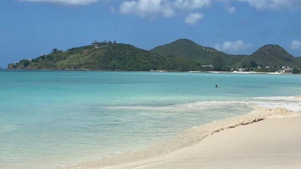 A beach with clear turquoise water, sandy shore, and green hills in the background. - 4 Guests - Stunning View - Pool - South Finger (Jolly Harbour)