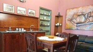 A kitchen with wooden cabinets, a sink, and a dining area with a table and chairs. - Casa Castelli Holiday Apartment (Bagheria)