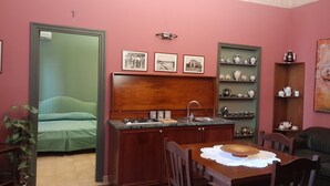 A compact living space with a kitchenette, a dining area, and a bed. - Casa Castelli Holiday Apartment (Bagheria)
