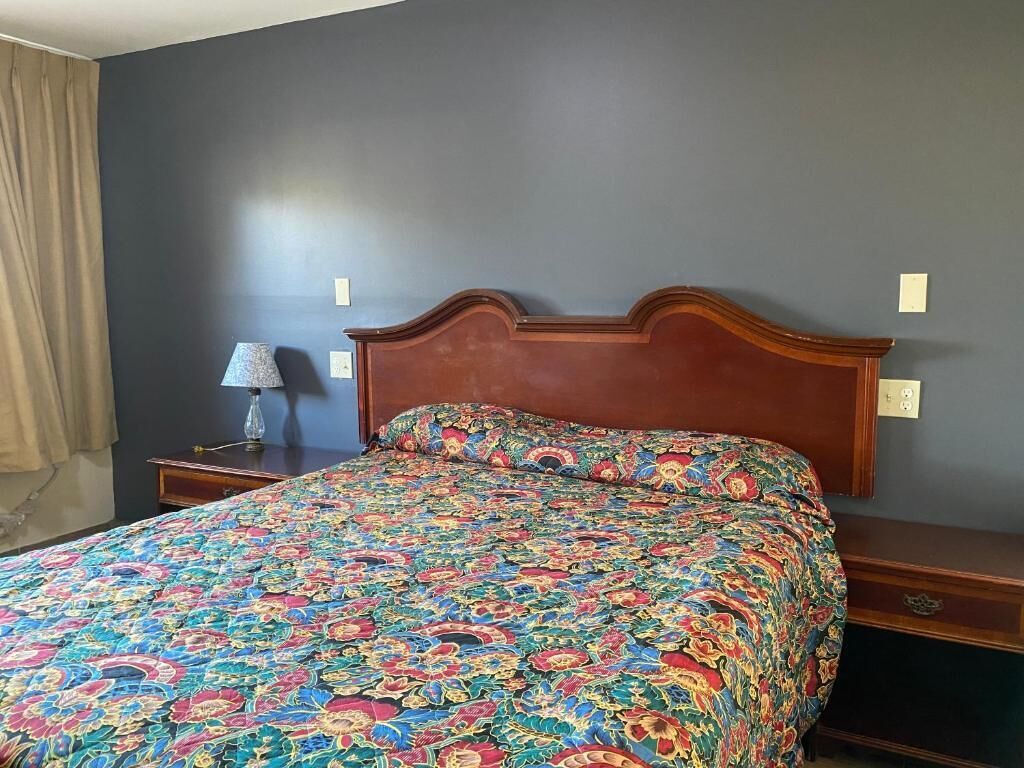 Une chambre à coucher avec un lit, une table de chevet, une lampe et une commode.