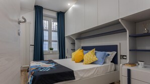 Ein modernes Schlafzimmer mit Bett, Nachttisch, Fenster mit Vorhängen und Einbauschränken.
