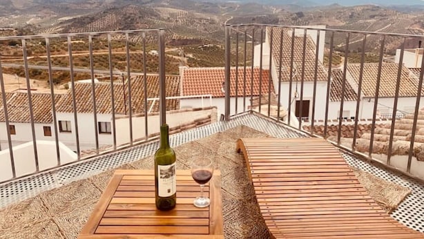 A terrace with a bottle of wine and a glass, overlooking a mountainous landscape. - Casa del Patito with Vista | Duckling Stays (Olvera)