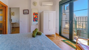 A bedroom with a bed, a wardrobe, a door leading to a balcony, and a wall-mounted air conditioner. - Casa del Patito with Vista | Duckling Stays (Olvera)