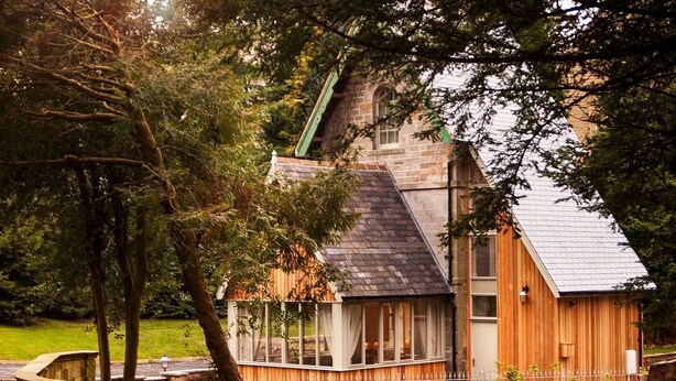 Ein rustikales Holzhaus mit geneigtem Dach, einer Glaseinfassung und einer Steinwand.
