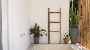 A spa area with a tiled bathtub, a wooden ladder, and potted plants. - Koserê (Ilhabela)