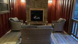 A cozy room with a stone fireplace, wicker furniture, and wooden walls. - Knotty Pine cabin, Couples Retreat w/ Hot Tub
And Patio Gas log Fireplace. (Jasper)