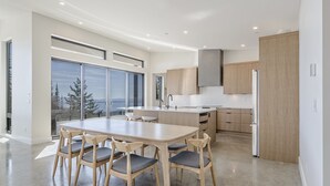 Una cuina moderna amb una illa central, armaris de fusta i una finestra gran que ofereix vistes a arbres.